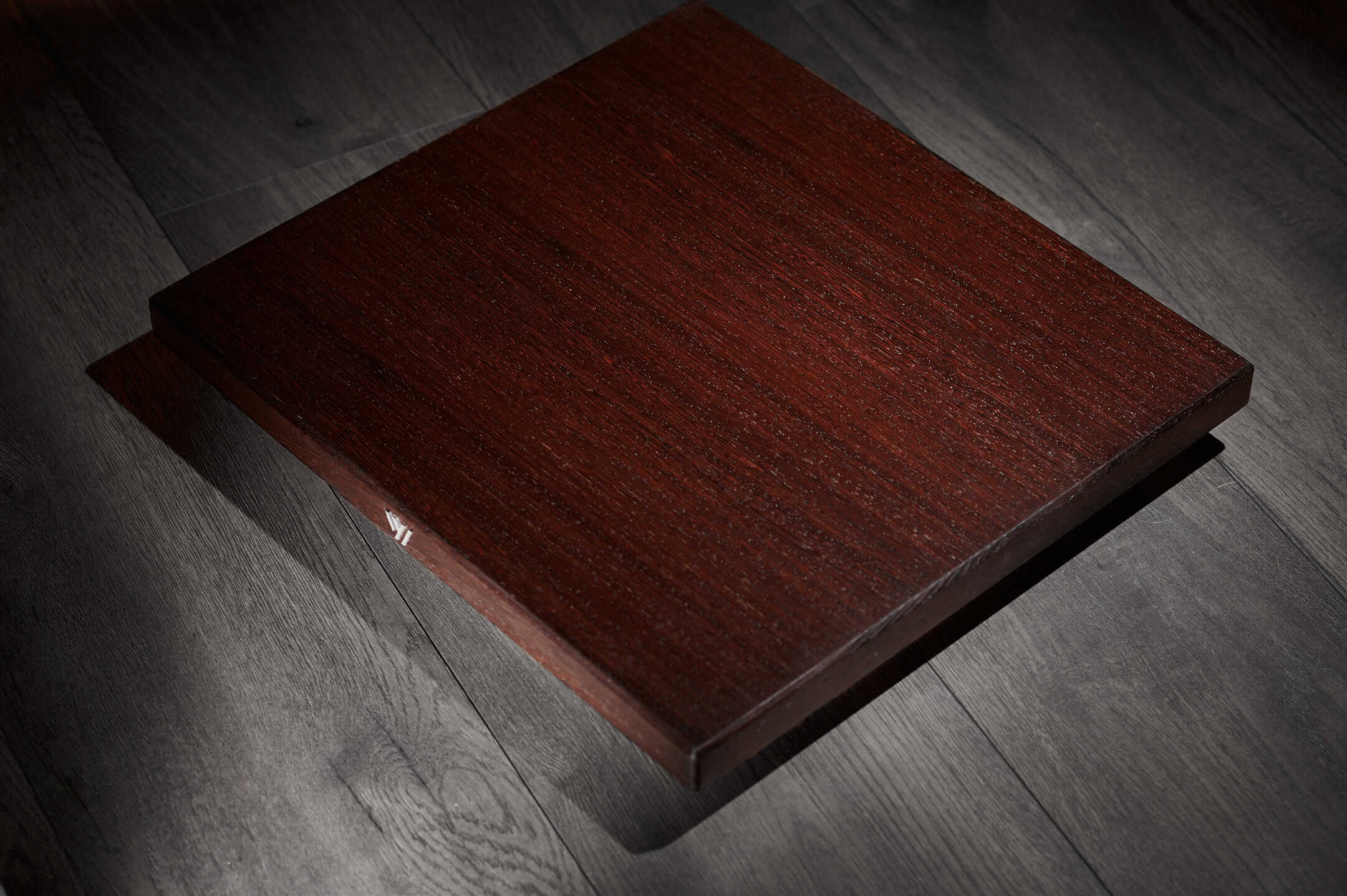 Polished dark wooden flooring sample with rich grain texture.