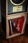 Wooden speaker stand with vinyl record holder for home audio setup.